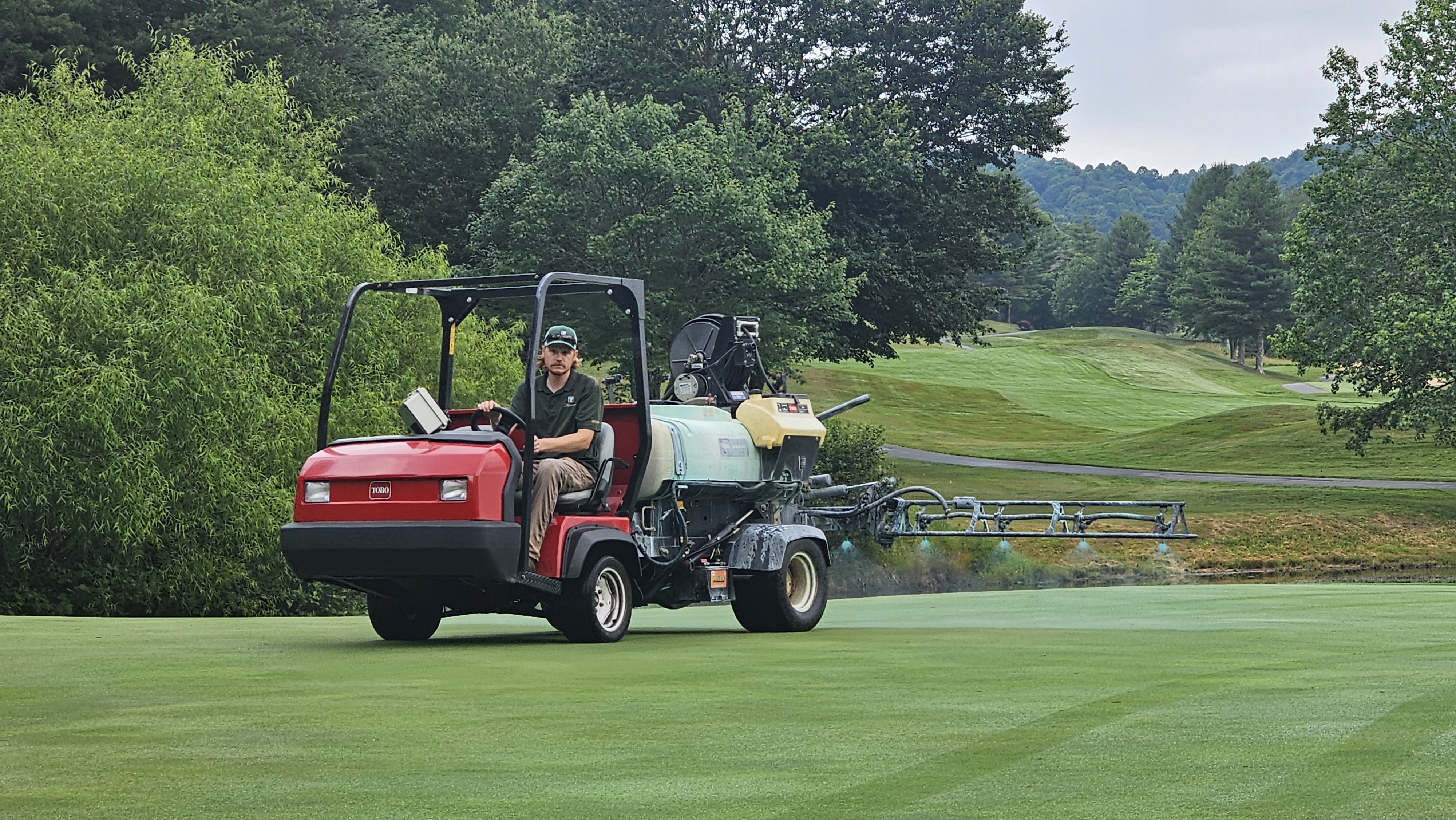 Austin operating a Toro Multi Pro sprayer with booms extended